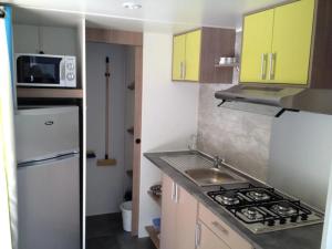 a kitchen with yellow cabinets and a white refrigerator at Camping 3 étoiles - Piscine - eehhec in Landry