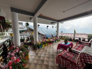a balcony with tables and flowers and a view of a mountain at V V Homestay in Darjeeling