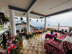 a patio with flowers and tables and a view of a mountain at V V Homestay in Darjeeling