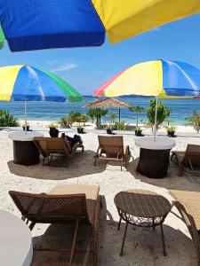 - un groupe de tables et de chaises avec parasols sur la plage dans l'établissement Whitesands Beach Resort, à San Isidro