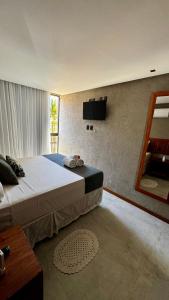 a bedroom with a large bed and a television at Patacho Brisa Mar - Triplex na Rota Ecológica dos Milagres in Pôrto de Pedras +30 photos