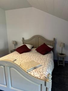 a white bed with red pillows and a book on it at Coeur d'Argonne in Dombasle-en-Argonne