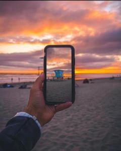 een persoon die een mobiele telefoon omhoog houdt om een foto van het strand te maken bij 5N-31 Beach View BBQ & Jacuzzi in Oceanside