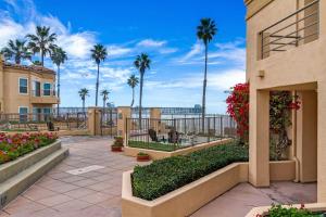 een patio met palmbomen en bloemen en een gebouw bij 5N-31 Beach View BBQ & Jacuzzi in Oceanside