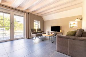 a living room with a couch and a tv at Villa Linde | 4 personen - Vakantiepark De Kremmer in Gasselte