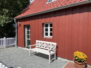 einer Bank, die außerhalb eines roten Gebäudes sitzt in der Unterkunft Ferienhaus in Zimmert mit Terrasse, Grill und Garten in Rieseby