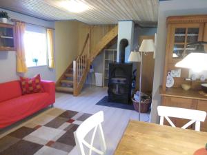 ein Wohnzimmer mit einem roten Sofa und einem Holzofen in der Unterkunft Ferienhaus in Zimmert mit Terrasse, Grill und Garten in Rieseby