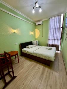 ein Schlafzimmer mit einem Bett und einem Stuhl und einem Fenster in der Unterkunft Eurasia Turkestan in Türkistan