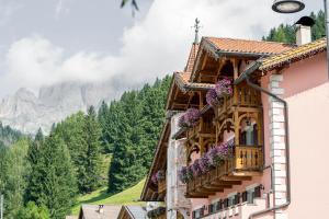 ein Gebäude mit Blumen auf dem Balkon mit einem Berg in der Unterkunft EL CIASEL in Canazei