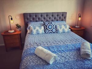 a bedroom with a bed with a blue and white comforter at Seafoam, Cowes, New Home, Fast NBN WIFI in Cowes