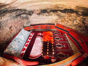 a cave with colorful blankets and pillows at Little Petra Bedouin Camp in Al Ḩayy