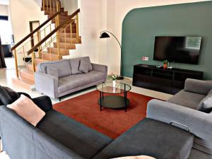 un salon avec deux canapés et une télévision à écran plat dans l'établissement UniVilla- Ideal Family Home for 18pax, à Gelugor