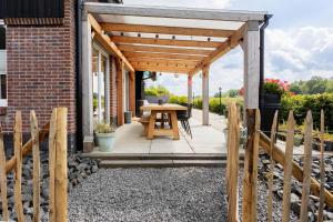 a wooden pergola with a table on a patio at Villa Crème de la Kremmer met Hottub & Sauna | 8 personen in Gasselte