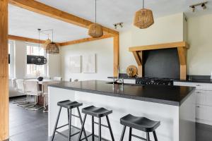 a kitchen with a black counter top and stools at Villa Crème de la Kremmer met Hottub & Sauna | 8 personen in Gasselte