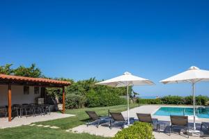 a patio with chairs and umbrellas next to a pool at Ferienvilla Malvasia Mit Swimmingpool Auf Kreta in Roúpai