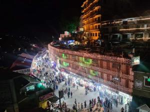 un groupe de personnes marchant la nuit dans une rue de la ville dans l'établissement Al Maz Hotel Mall Road, à Dargai