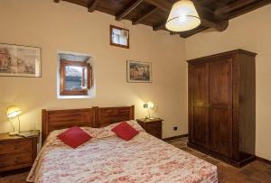 ein Schlafzimmer mit einem Bett mit zwei roten Kissen in der Unterkunft Freistehendes Agriturismo in der Toskana für sechs Personen mit großem gemeinschaftlich genutzten Garten und Pool in Pratovecchio
