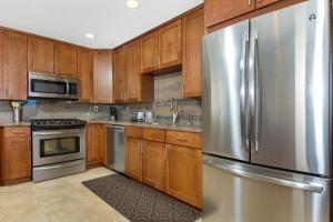 une cuisine avec des armoires en bois et un réfrigérateur en acier inoxydable dans l'établissement 5N-53 Beach Bliss Ocean Views, à Oceanside