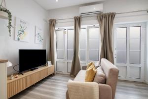 a living room with a couch and a television at Central Studio – Flor De Sol in Tavira