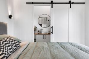 Schlafzimmer mit weißen Wänden, einem Bett und einem Spiegel in der Unterkunft Seabrook Vineyard Retreat 