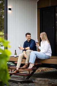Ein Mann und eine Frau sitzen mit Weingläsern an einem Picknicktisch. in der Unterkunft Seabrook Vineyard Retreat 