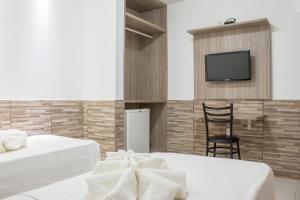 a room with two beds and a tv on a wall at Hotel Pousada Atlântica in João Pessoa