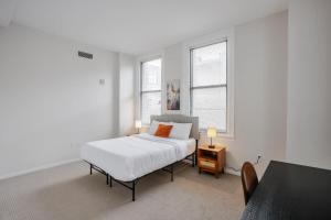 a white bedroom with a bed and two windows at TWO CozySuites Sky Central Rooftop Pool #25 in Cincinnati