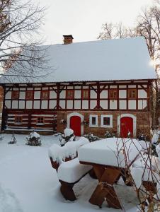 ein schneebedecktes Haus mit einem Tisch davor in der Unterkunft Chatka zimorodka in Pielgrzymka