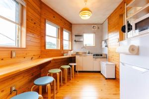 Una cocina con paredes de madera y suelos de madera y taburetes. en 長崎観光の拠点に最適グラバー園近くの一軒家ステイ, en Nagasaki
