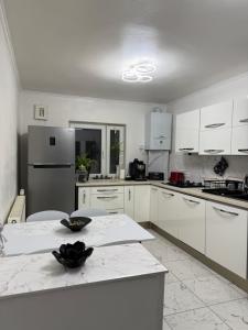 a white kitchen with white cabinets and a table at Apartament cozy corner in Caransebeş +13 photos