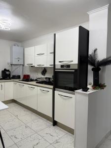 a kitchen with white cabinets and a black appliance at Apartament cozy corner in Caransebeş