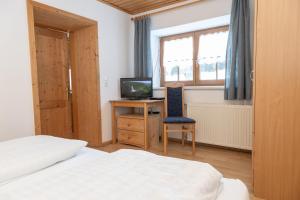 ein Schlafzimmer mit einem Bett und einem Schreibtisch mit einem Fernseher in der Unterkunft Ferienwohnung Schaupphof in Donnersbachwald