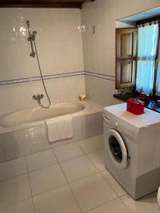 a bathroom with a tub and a washing machine at La Quintana del Sol in Aramil de Arriba