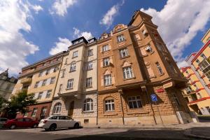 un grand bâtiment en briques avec des voitures garées devant lui dans l'établissement Apartment Karla Capka Street, à Karlovy Vary