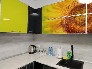 a kitchen counter with a sunflower painting on the wall at Vitosha view Mladost apartment in Sofia +11 photos