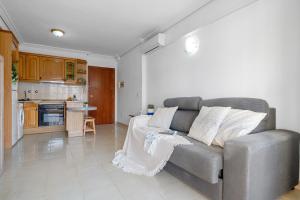 Una sala de estar con un sofá y una cocina. en Apartamentos ALBENIZ - La Pineda Platja, en La Pineda