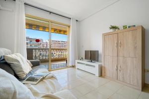 Una sala de estar con un sofá y una ventana grande. en Apartamentos ALBENIZ - La Pineda Platja, en La Pineda