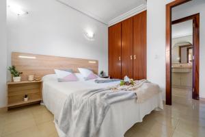 Un dormitorio con una gran cama blanca con flores. en Apartamentos ALBENIZ - La Pineda Platja, en La Pineda