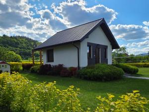 ein kleines weißes Haus auf einem Grasfeld in der Unterkunft Domek GORCZAŃSKA KOLIBA w Gorcach in Kamienica