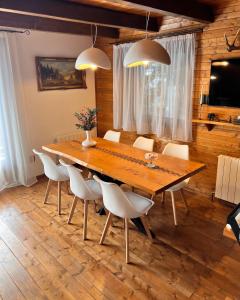 ein Esszimmer mit einem Holztisch und weißen Stühlen in der Unterkunft Chalet A Baisoara - Piscină încălzită - Pârtii în apropiere in Băişoara