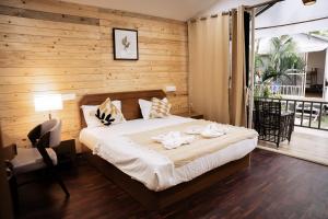 a bedroom with a bed with a wooden wall at Sameer beachfront Cottages in Canacona