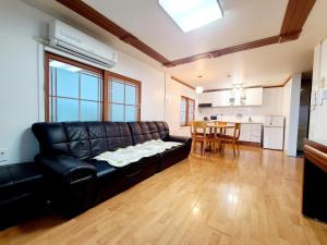 a living room with a black leather couch and a table at Jeju Castle in Seogwipo