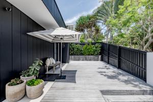 une terrasse avec un parasol et un banc dans l'établissement Mimosa by the Beach, à Peregian Beach