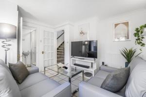 ein weißes Wohnzimmer mit einem Sofa und einem TV in der Unterkunft 4 Bedroom Elegant House Near Peterborough City Center with Free Parking - Angus Suites by Contractor Lettings in Peterborough