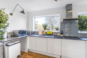 eine Küche mit weißen Schränken und einer blauen Arbeitsplatte in der Unterkunft 4 Bedroom Elegant House Near Peterborough City Center with Free Parking - Angus Suites by Contractor Lettings in Peterborough