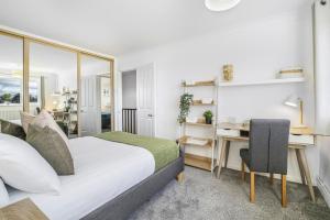 ein Schlafzimmer mit einem Bett und einem Schreibtisch mit einem Computer in der Unterkunft 4 Bedroom Elegant House Near Peterborough City Center with Free Parking - Angus Suites by Contractor Lettings in Peterborough