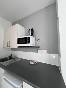 a kitchen with a microwave above a counter at TLK Apartments & Hotel - Beckenham in Beckenham +34 photos