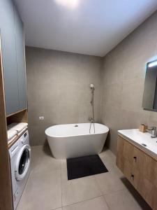 a bathroom with a tub and a washing machine at C&E Apart in Craiova