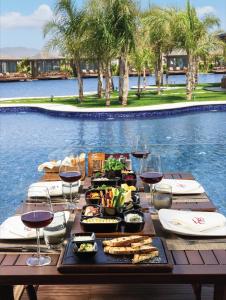 ein Tisch mit Essen und Weingläsern neben einem Pool in der Unterkunft Grand Sapphire Hotel, Casino & Holiday Deluxe Residential Home in Iskele