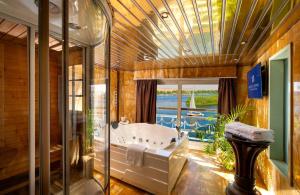 ein großes Bad mit einer Badewanne und einem großen Fenster in der Unterkunft Sonesta St George Nile Cruise - Aswan to Luxor 3 Nights from Friday to Monday in Assuan